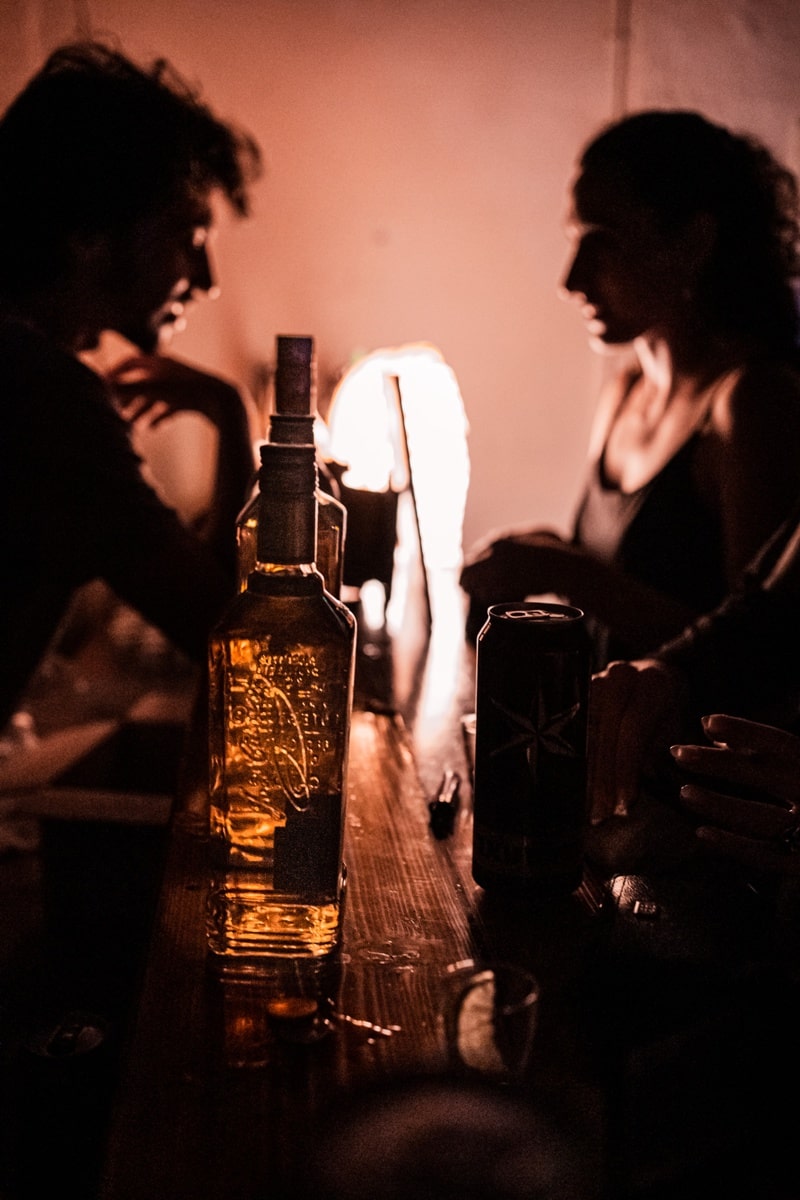 שני צלליות של בחורים יושבים ומדברים בבר ליד בקבוק אלכוהול צילום תדמית לעסק ולברים